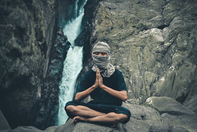 Young man sitting on rock