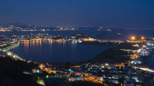 High angle view of illuminated city buildings against sky at night