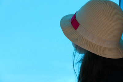 Rear view of woman wearing hat against blue sky