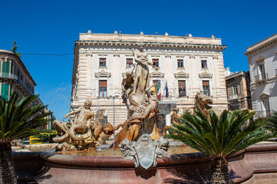 Statue by building against clear sky