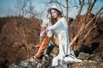 Portrait of fashionable woman sitting on rock