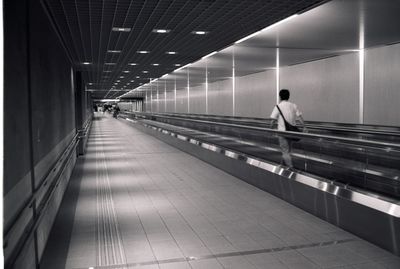 Rear view of man walking on escalator