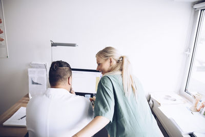 Rear view of female nurse and male doctor discussing at office in hospital