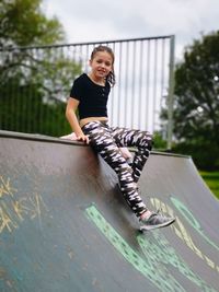 Full length portrait of girl sitting at skateboard ramp