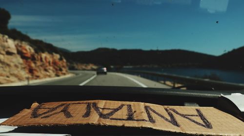 Road sign against sky seen through car windshield