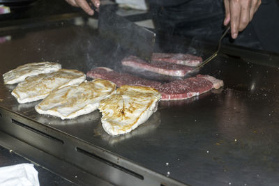 High angle view of person cooking chicken breasts at restaurant