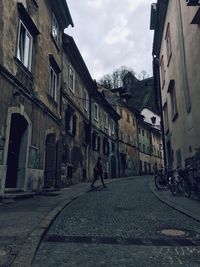 Man walking on road along buildings