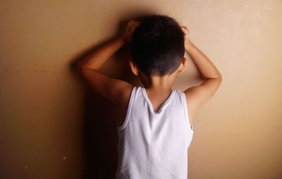 Rear view of boy standing in front of wall at home