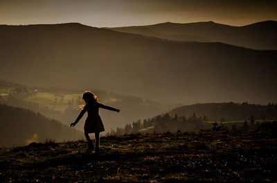 Silhouette woman standing on field against sky during sunset