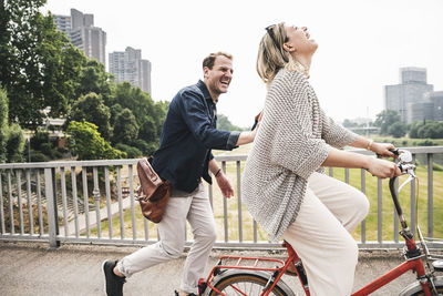 Happy couple crossing a bridge with bicycle and by foot