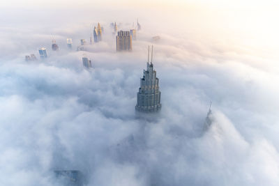 Aerial view of buildings in city against cloudy sky