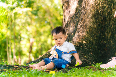 Cute boy sitting on tree trunk