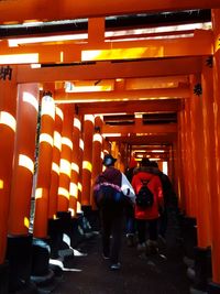 Rear view of people walking in illuminated corridor