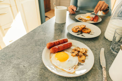 Breakfast set of sausages fried eggs and mushroom with fresh milk and cookies.