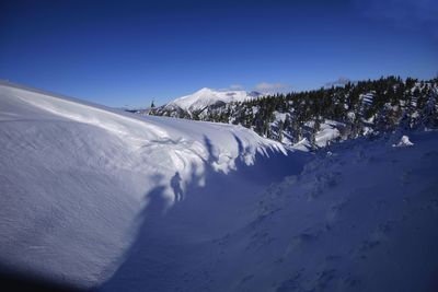 Snow covered mountain against blue sky