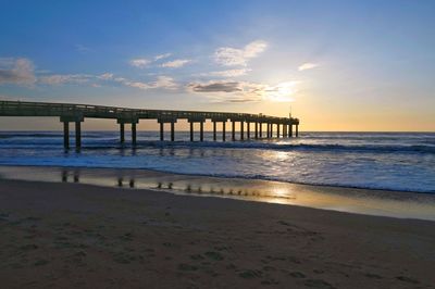 Pier over sea against sky during sunset