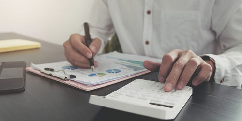 Midsection of man holding paper on table