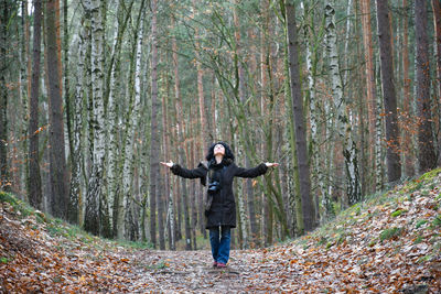 Full length of woman with arms outstretched standing in forest