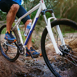 Low section of man riding bicycle on field