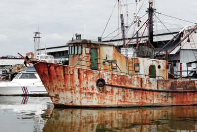 Fishing boats moored at harbor against sky