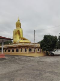 Statue by building against sky