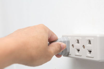Close-up of man hand against white wall