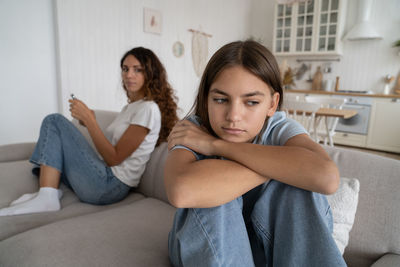 Unhappy mother parent and teenage daughter ignoring each other after fight at home