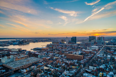 High angle view of buildings by sea against sky during sunset