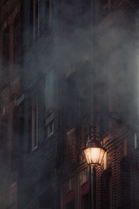 Low angle view of illuminated street light against building at night