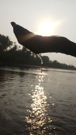 Silhouette of woman in lake against sky during sunset