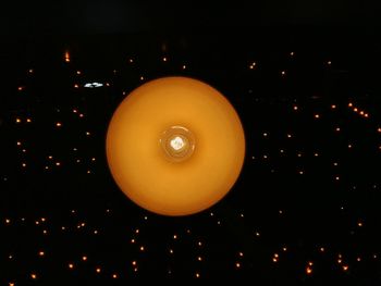 Low angle view of illuminated light bulb against sky at night