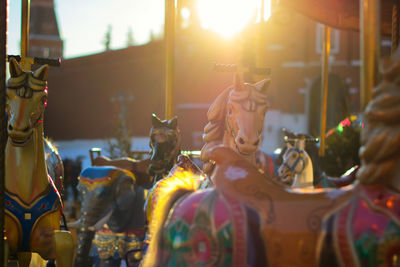 Close-up of carousel horses at amusement park during sunset