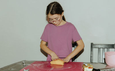One girl bakes cookies, kneading the dough with her hands on the table.