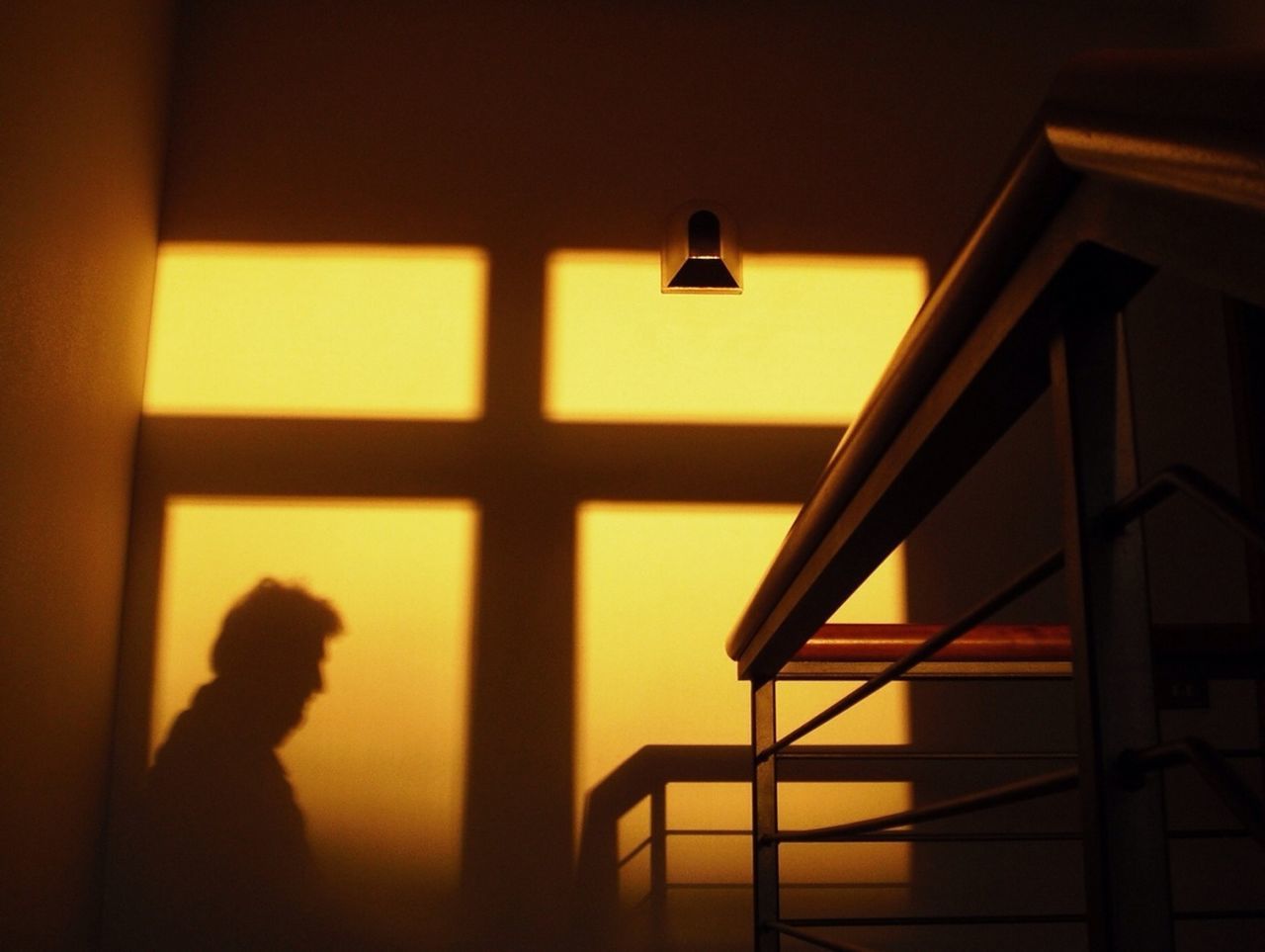 indoors, lifestyles, window, illuminated, home interior, leisure activity, men, person, silhouette, unrecognizable person, sitting, chair, glass - material, lighting equipment, shadow, standing, wall - building feature, architecture