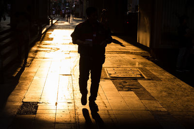 Rear view of woman walking on sidewalk in city at night