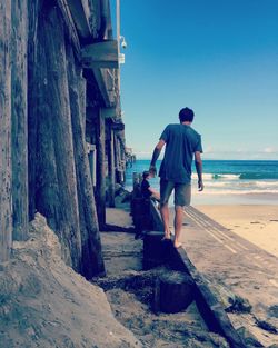 Rear view full length of man walking by pier at beach