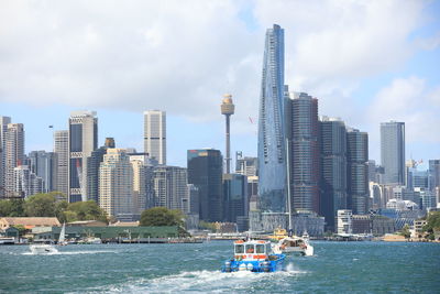Boats in sea by buildings against sky