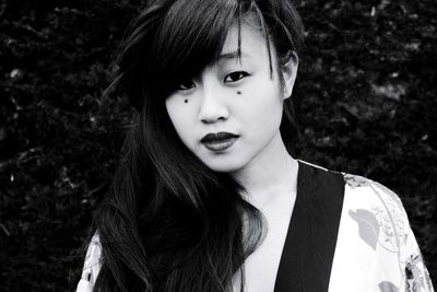 Close-up portrait of young woman standing against trees