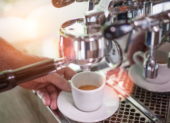 Close-up of person holding cup at espresso maker 