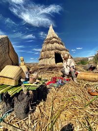 Woman wearing sunglasses sitting by hut against sky