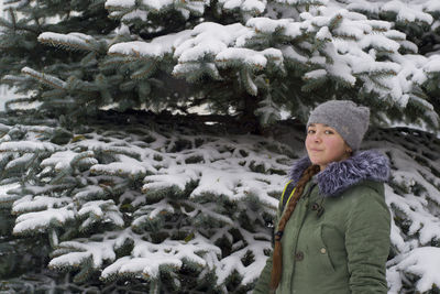 Portrait of girl standing in front of snow covered tree