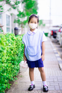 Portrait of smiling girl standing on footpath