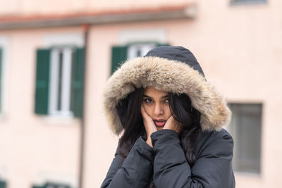 Cute young woman freezing in winter coat standing in the street