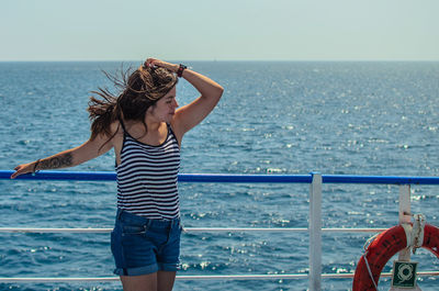 Woman standing in sea against sky