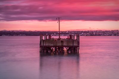 Pier over sea against sky during sunset