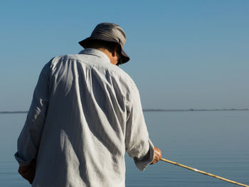 Rear view of man fishing in sea