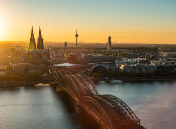 Aerial view of arch bridge over river against sky during sunset