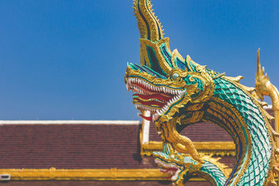 Low angle view of statue against building against clear blue sky