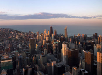 High angle view of cityscape by sea against sky during sunset