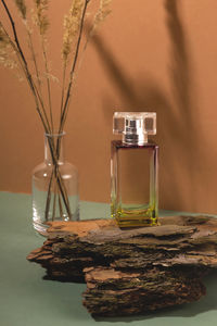 Close-up of perfume bottle in glass on tree bars with vase of dry flowers. natural aroma 